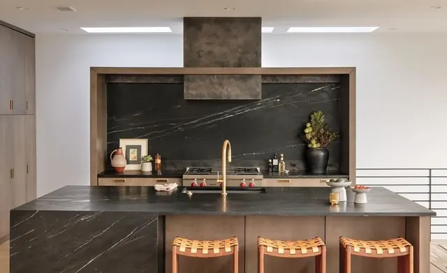Dark stone kitchen island with a rangetop under a hood